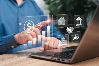 © NongAsimo - stock.adobe.com Foto: Laptop mit Symbolen zu Immobilien davor