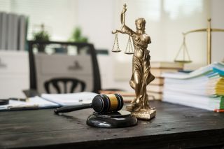 © NanSan - stock.adobe.com Foto: Justitia Statue auf Schreibtisch